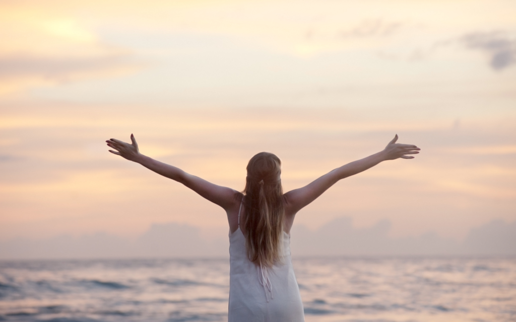 海辺で手を広げる女性